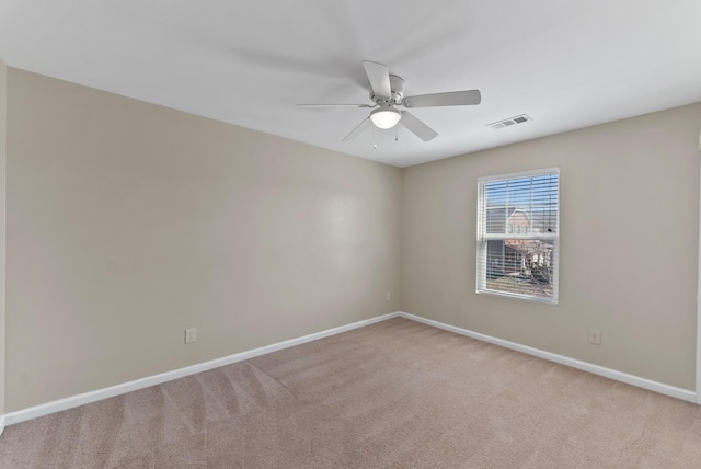 spare room with light carpet, ceiling fan, visible vents, and baseboards