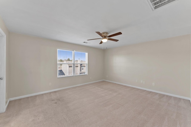 spare room with light carpet, visible vents, and a ceiling fan