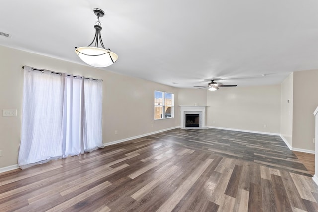 unfurnished living room featuring a fireplace with flush hearth, baseboards, and wood finished floors