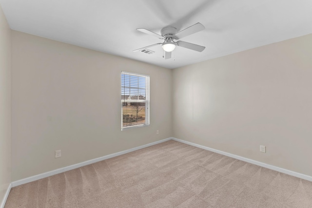 spare room featuring baseboards, visible vents, ceiling fan, and light colored carpet