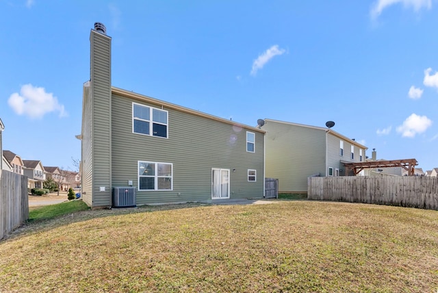 back of property featuring a chimney, fence, a lawn, and central AC unit