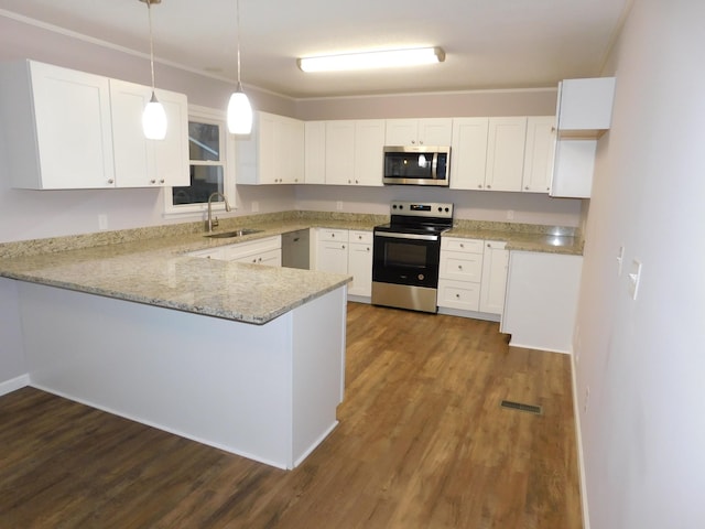 kitchen featuring appliances with stainless steel finishes, a peninsula, dark wood-style floors, white cabinets, and a sink