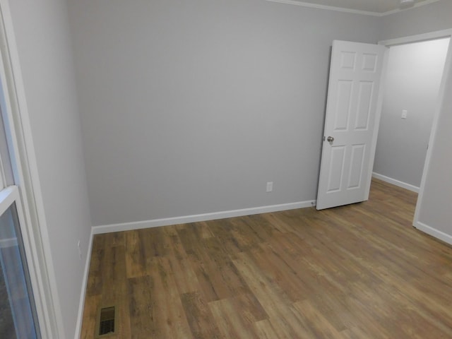 unfurnished room featuring ornamental molding, wood finished floors, visible vents, and baseboards