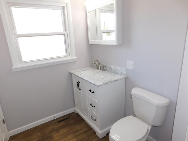 bathroom featuring vanity, wood finished floors, baseboards, visible vents, and toilet