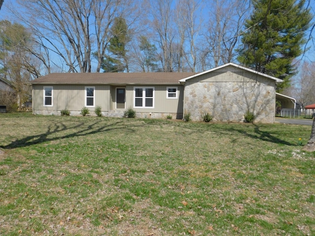 ranch-style house featuring stone siding, a detached carport, and a front lawn