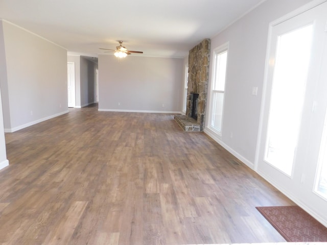 unfurnished living room featuring ceiling fan, plenty of natural light, dark wood finished floors, and a fireplace