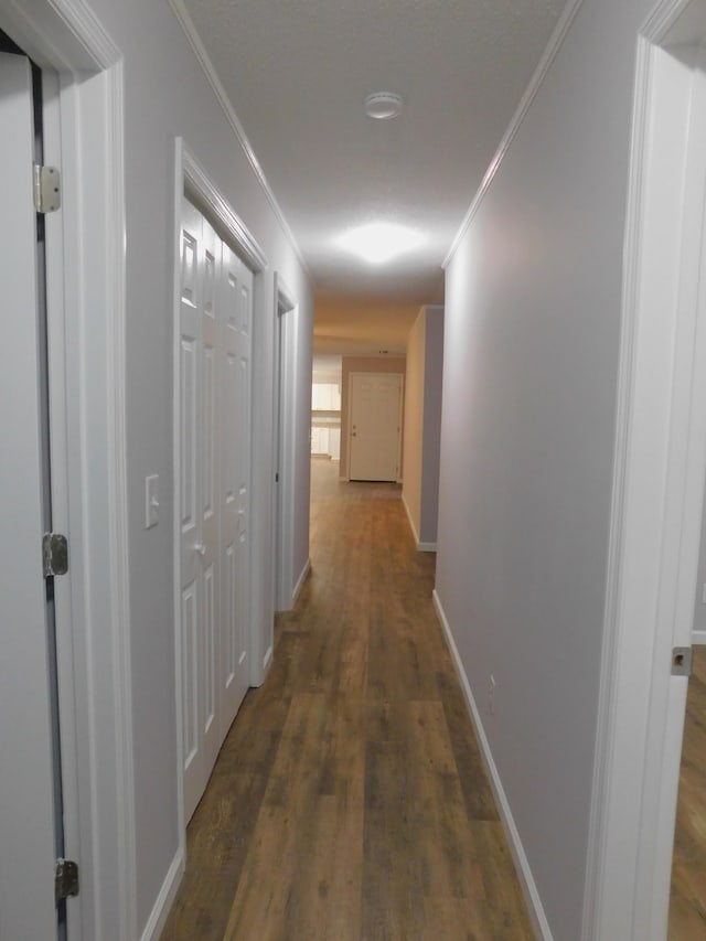 hallway with crown molding, wood finished floors, and baseboards