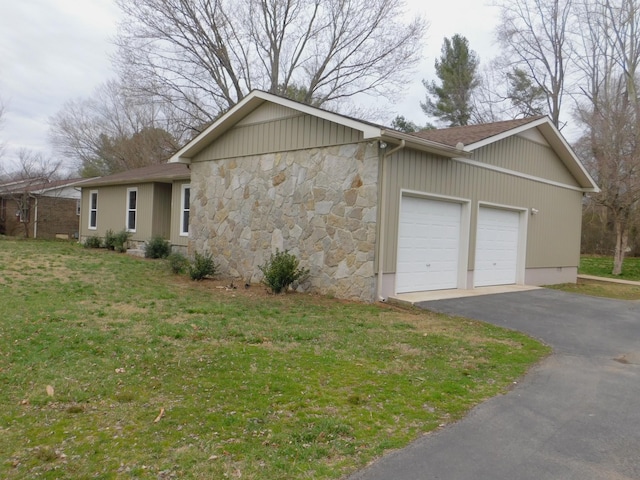 view of property exterior with a garage, stone siding, a lawn, and driveway