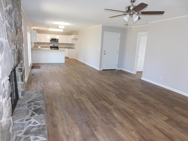 unfurnished living room with baseboards, a stone fireplace, ornamental molding, and dark wood finished floors