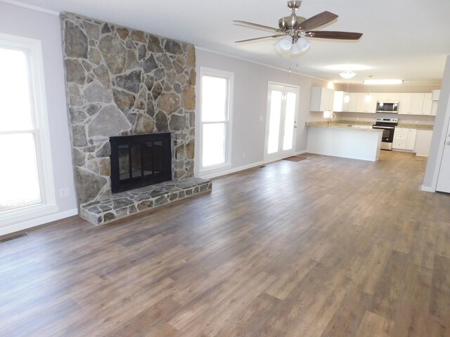 unfurnished living room with dark wood-type flooring, ceiling fan, a fireplace, and crown molding