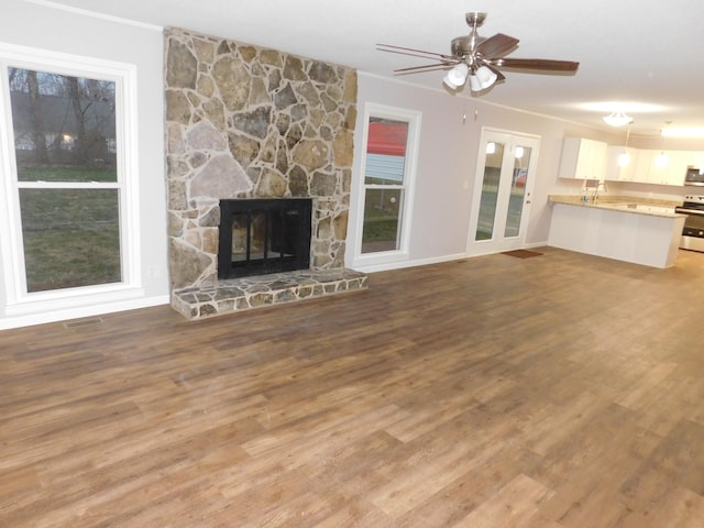 unfurnished living room featuring a ceiling fan, wood finished floors, visible vents, a fireplace, and a sink