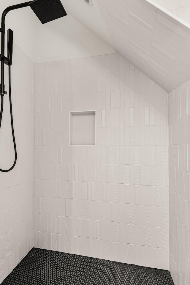 bathroom with vaulted ceiling and a tile shower