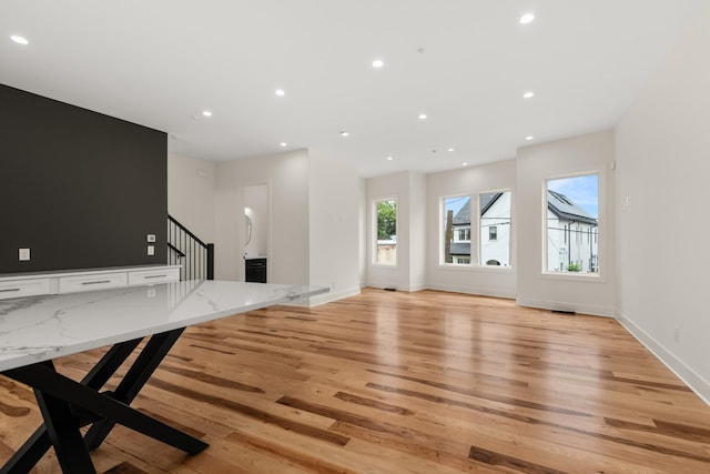 unfurnished living room featuring stairs, light wood finished floors, baseboards, and recessed lighting