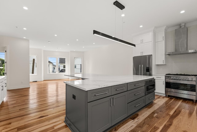 kitchen featuring wall chimney exhaust hood, high quality appliances, a center island, gray cabinets, and white cabinetry