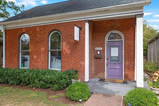 property entrance with brick siding and roof with shingles