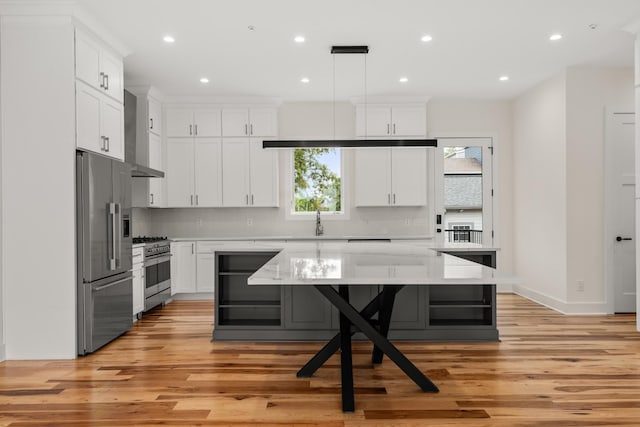 kitchen with appliances with stainless steel finishes, light countertops, wall chimney exhaust hood, and tasteful backsplash