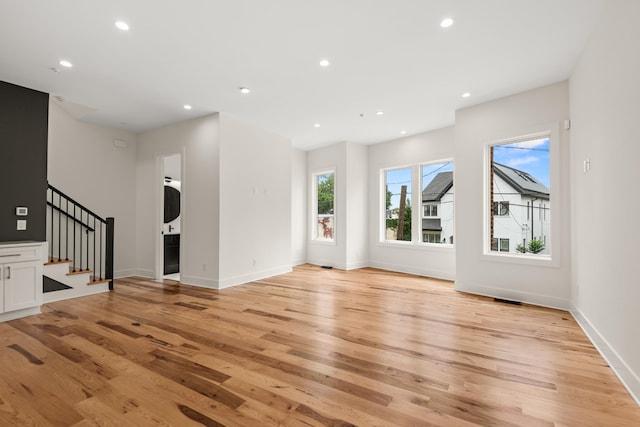 unfurnished living room with light wood-style floors, stairs, baseboards, and recessed lighting