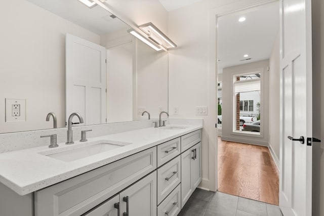 full bath with baseboards, double vanity, a sink, and recessed lighting