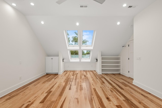 additional living space featuring lofted ceiling with skylight, baseboards, visible vents, and light wood finished floors