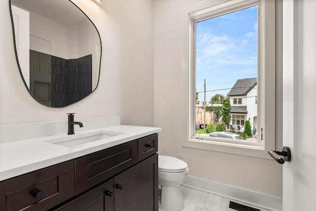 bathroom with toilet, baseboards, visible vents, and vanity