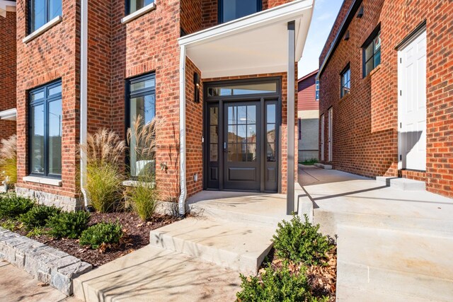 doorway to property featuring covered porch and brick siding