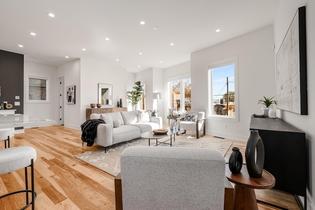 living room with light wood-style floors, baseboards, visible vents, and recessed lighting