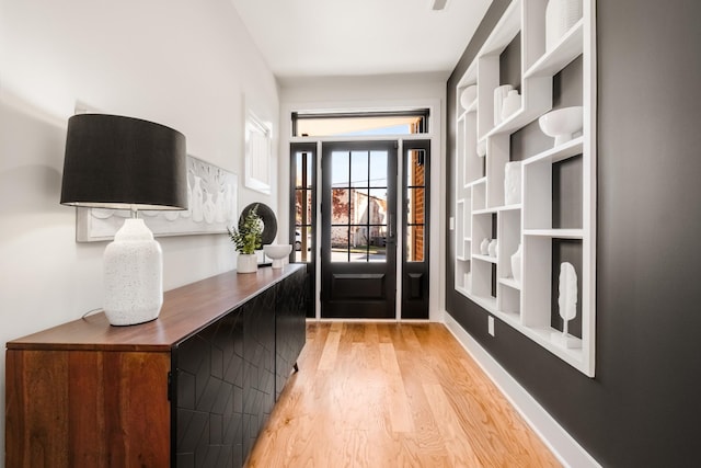 doorway with light wood-type flooring and baseboards