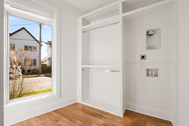 washroom with baseboards, electric dryer hookup, and light wood-style floors