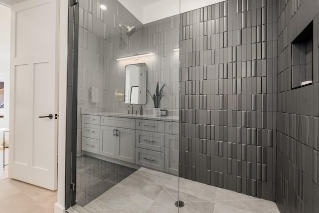 bathroom with tile patterned flooring, tiled shower, and vanity