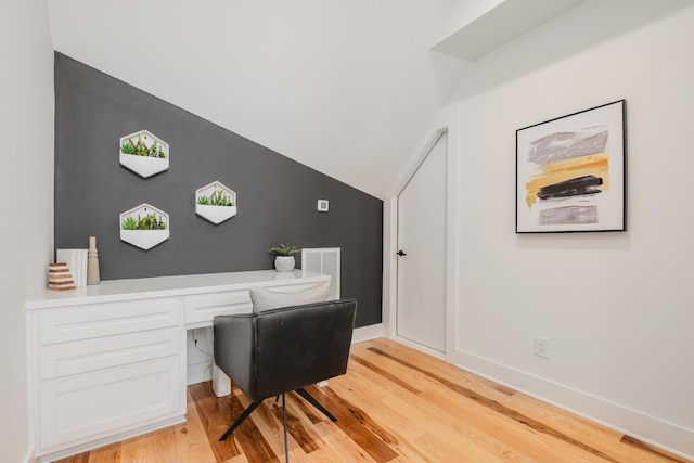 office with lofted ceiling, visible vents, baseboards, light wood-type flooring, and built in desk