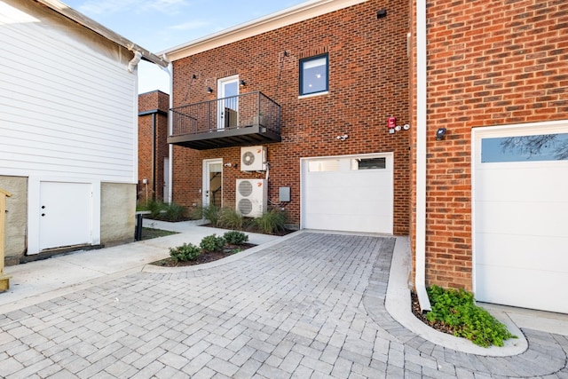 exterior space with a garage, decorative driveway, brick siding, and a balcony