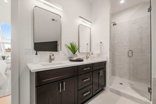 bathroom featuring double vanity, a stall shower, a sink, and visible vents