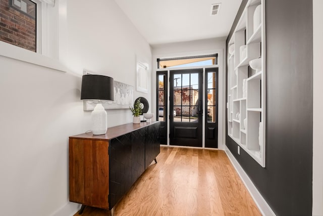 interior space with light wood-style flooring, visible vents, and baseboards