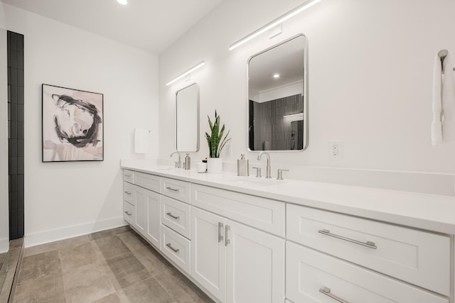 full bathroom featuring double vanity, baseboards, and a sink