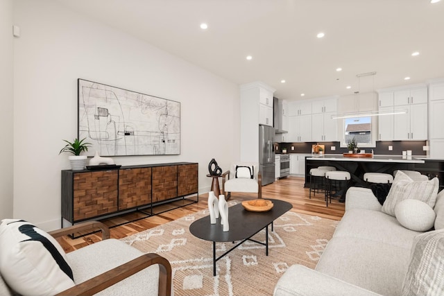 living room featuring baseboards, light wood-type flooring, and recessed lighting