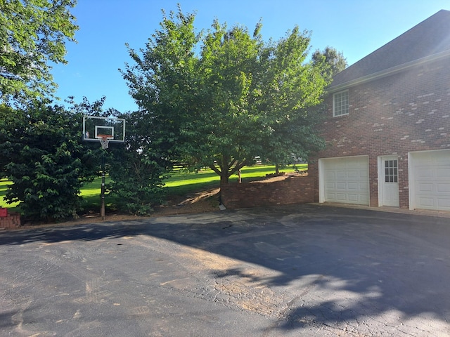 view of home's exterior with aphalt driveway, brick siding, and an attached garage