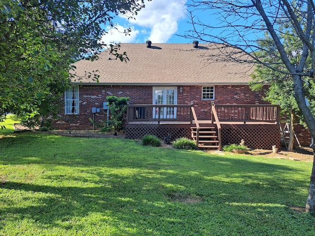 back of house featuring a shingled roof, brick siding, a lawn, and a deck