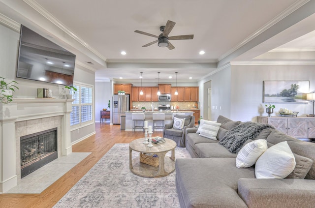 living area with recessed lighting, a tiled fireplace, light wood-style flooring, and a ceiling fan