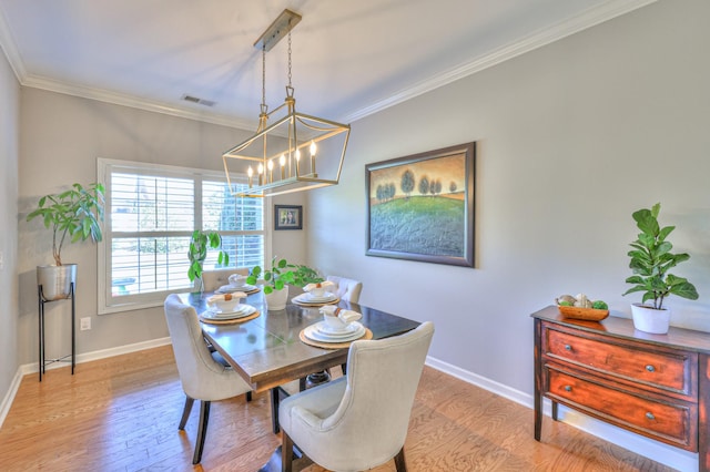 dining area featuring baseboards, visible vents, ornamental molding, and wood finished floors