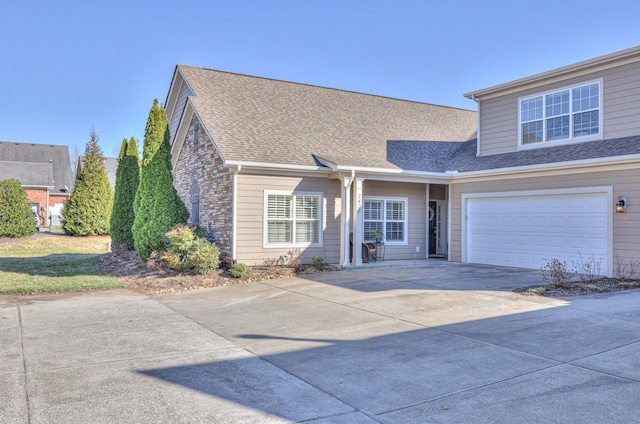 view of front of home with roof with shingles, driveway, and an attached garage