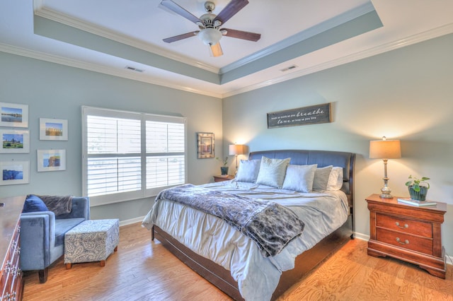 bedroom featuring wood finished floors, a raised ceiling, and visible vents