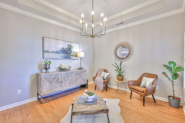 living area with a notable chandelier, wood finished floors, visible vents, a raised ceiling, and crown molding