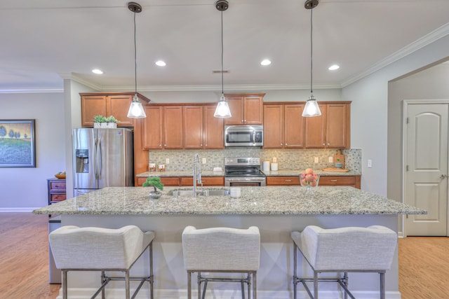 kitchen with brown cabinets, stainless steel appliances, decorative backsplash, a sink, and light wood-type flooring