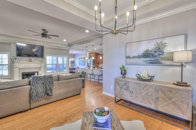 living area featuring a tiled fireplace, ornamental molding, plenty of natural light, and wood finished floors