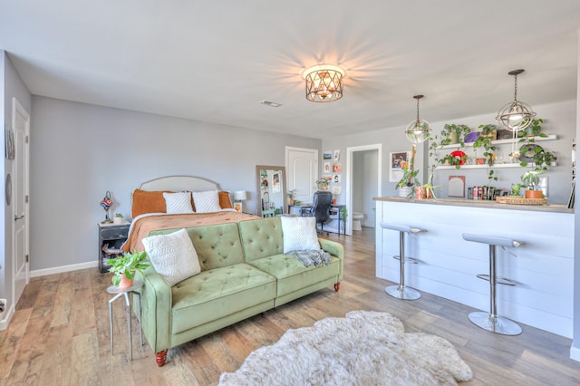 bedroom with wood finished floors, visible vents, and baseboards