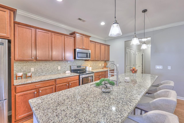 kitchen with tasteful backsplash, a center island with sink, stainless steel appliances, crown molding, and a sink