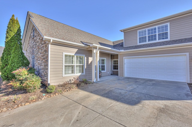 view of front facade featuring a garage, concrete driveway, roof with shingles, and stone siding