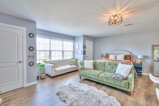 bedroom featuring baseboards, visible vents, and wood finished floors