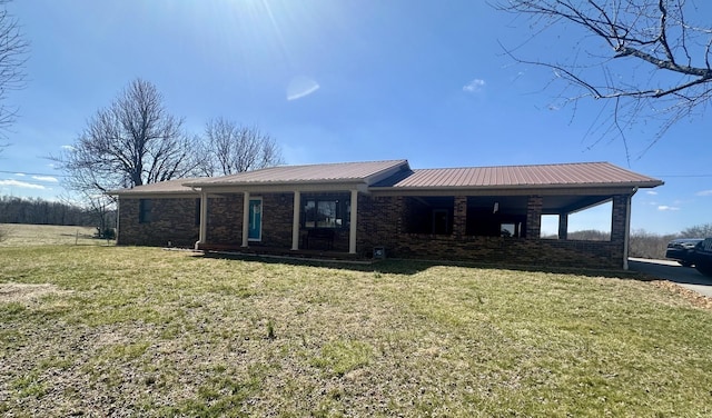 view of front of property featuring metal roof, brick siding, and a front yard