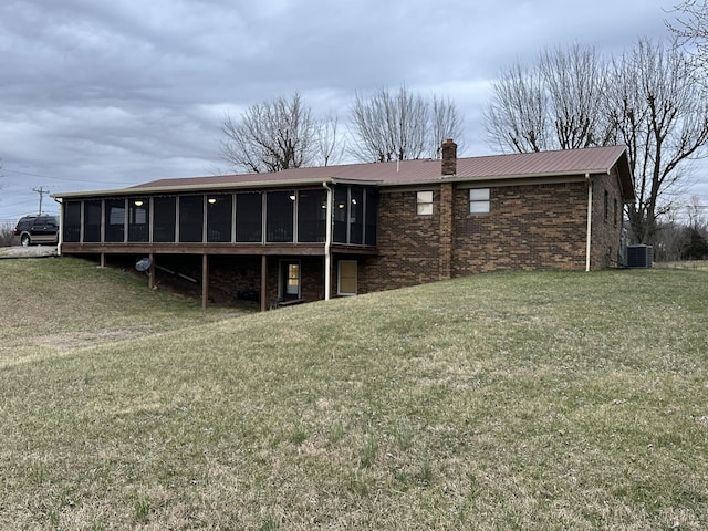 back of house with a sunroom, brick siding, metal roof, and a chimney